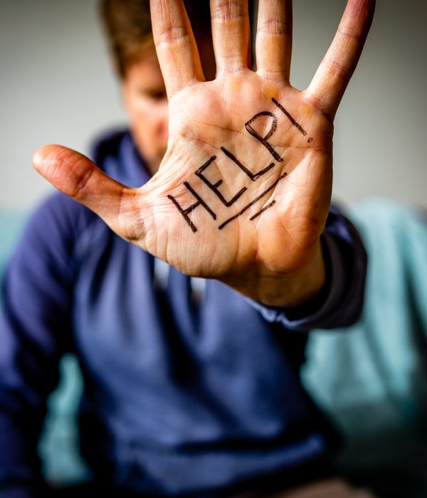 Man holds hand to camera with HELP written on palm.